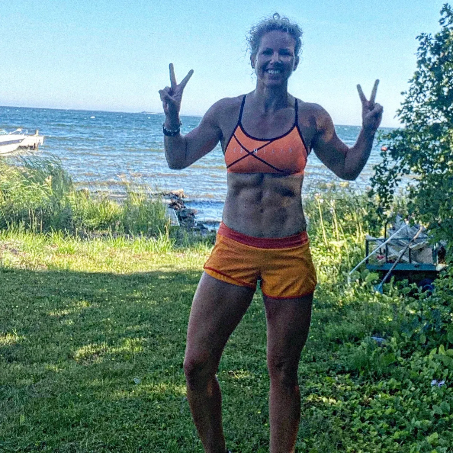 Charlotte gör segertecken i sommarsol vid vattnet